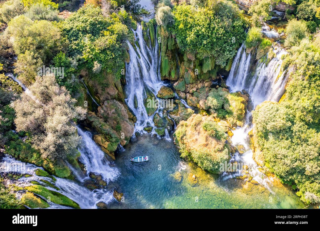 Kravica karst forest waterfall cascades flows with boat on the lake surface, Trebizat river, Bosnia and Herzegovina Stock Photo