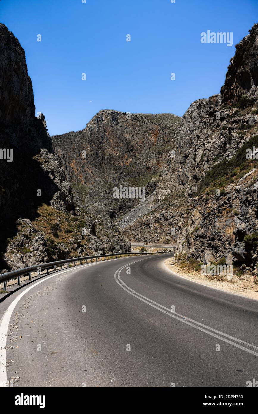 Let the rugged beauty of Crete surround you as you navigate this enchanting canyon road. Towering cliffs stand as sentinels, guiding your journey thro Stock Photo