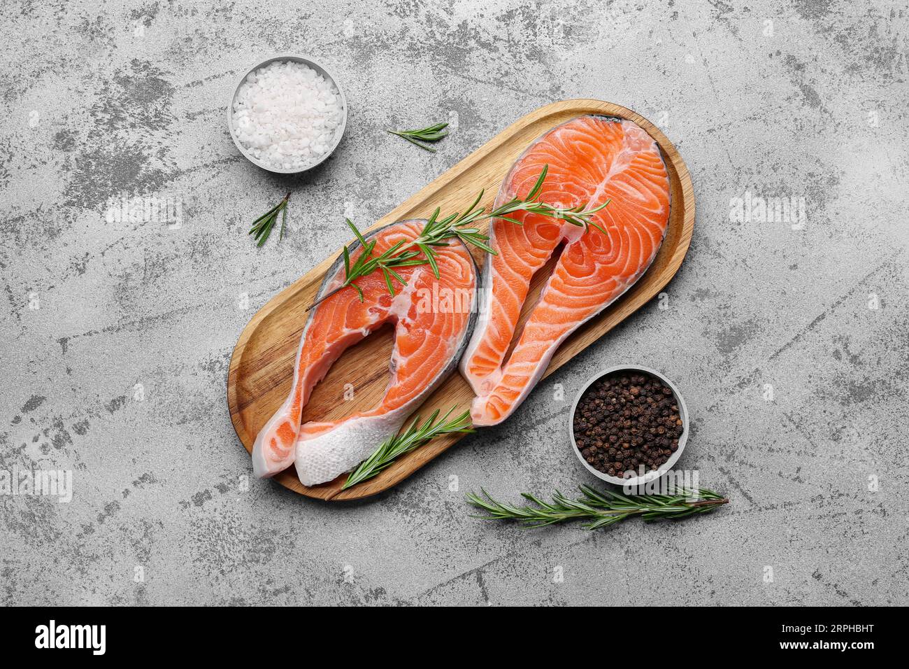 Wooden board with raw salmon steaks and different spices on blue ...