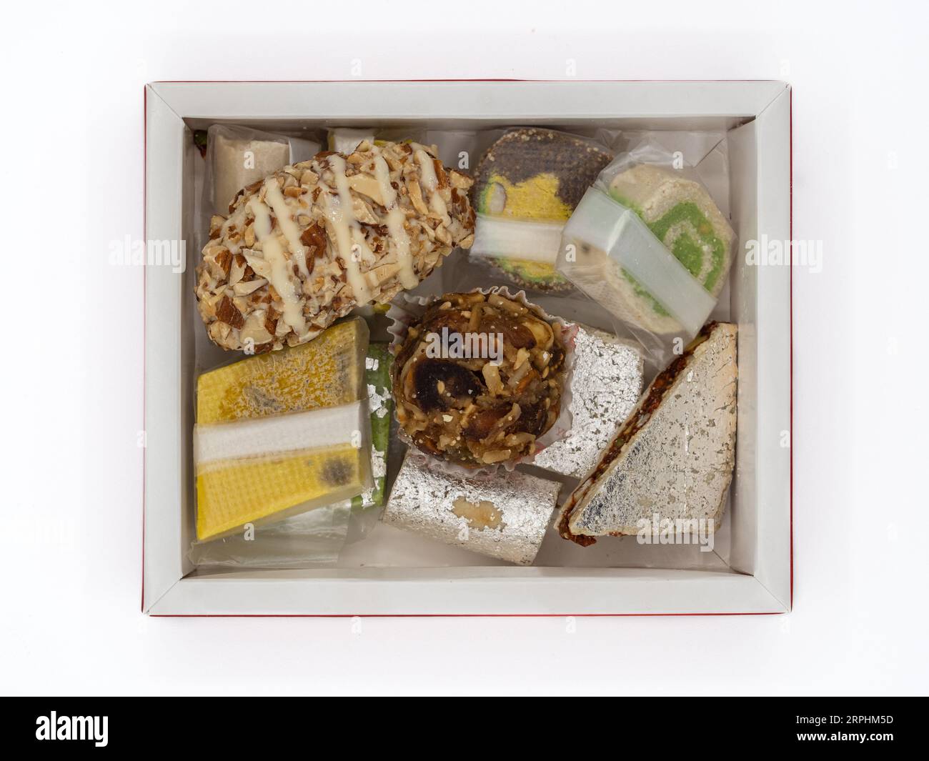 Top view of a box filled with assorted, delectable Indian ghee sweets, isolated on a white background. Stock Photo