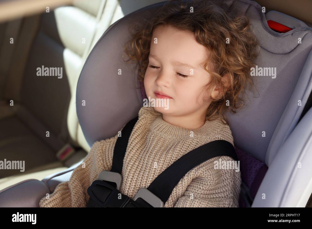 Cute little girl sleeping in child safety seat inside car Stock Photo
