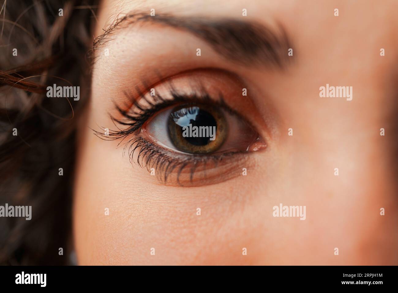 Ultra-close shot of a young woman's eye details. An eye resembling a universe, a star or a black hole capturing all light, yet drawing us in as if emi Stock Photo