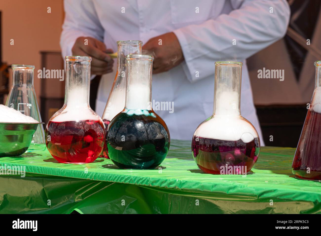 Laboratory glassware and test tubes with colorful liquids on glass table outdoors. Chemical reaction Stock Photo