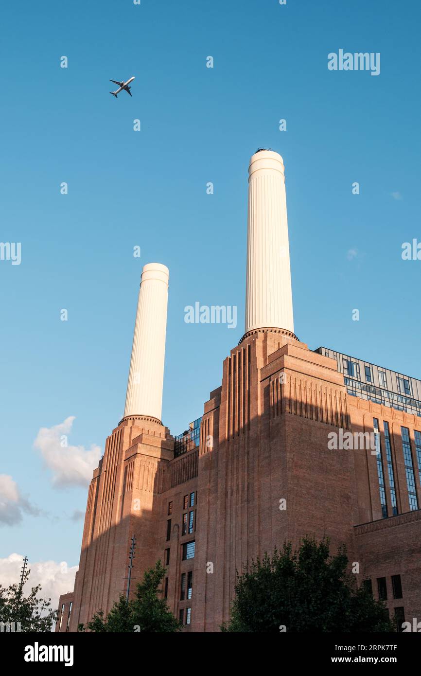 Battersea, London, England - 29th July 2023: A Qatar Airways plane flies past the iconic chimneys of Battersea Power Station in London against a blue Stock Photo