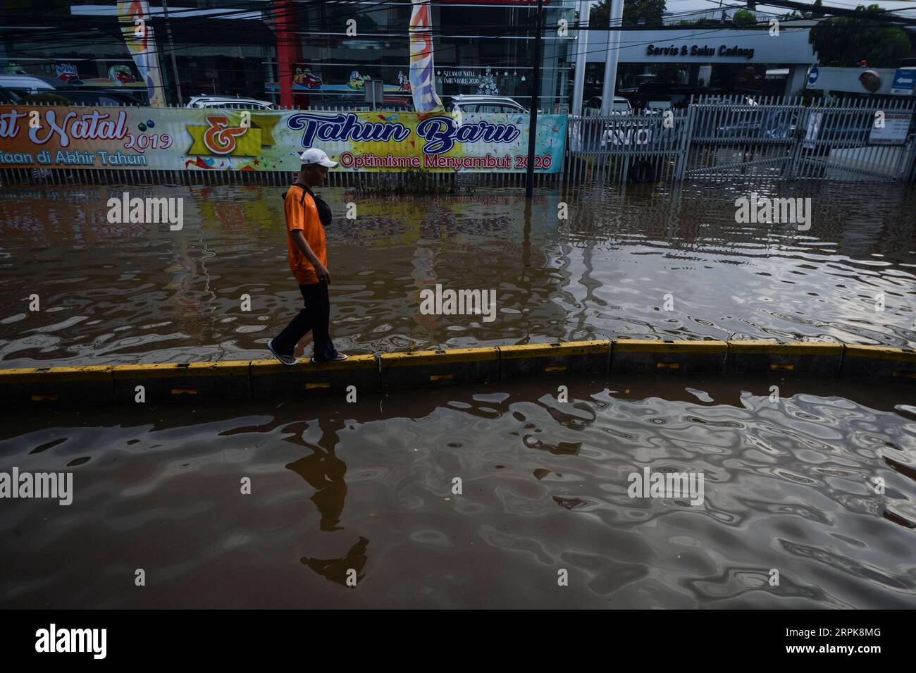 200102 -- JAKARTA, Jan. 2, 2020 -- A man walks on road barriers to cross a flooded area in Jakarta, Indonesia. Jan. 2, 2020. In Jakarta, evacuation of the flood-affected persons persisted as waters still submerged several parts of the city, and six people were reported dead in the city, said M. Ridwan, spokesman for a disaster agency in Jakarta.  INDONESIA-JAKARTA-FLOOD AgungxKuncahyaxB. PUBLICATIONxNOTxINxCHN Stock Photo