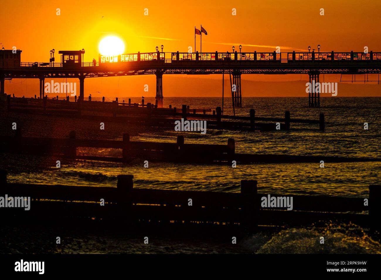 Worthing, West Sussex, UK. 5th Sep, 2023. People walk on the pier and photograph the sun rising as a heat-health alert has been issued for most parts of England - temperatures could reach 32C (89.6F) this week. The sun rising over Worthing pier photographed from Worthing Beach, UK on 5 September 2023 . Picture by Julie Edwards. Credit: JEP Celebrity Photos/Alamy Live News Stock Photo
