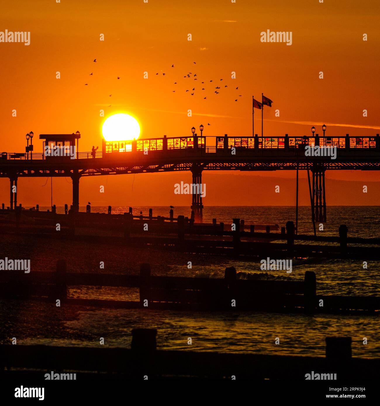 Worthing, West Sussex, UK. 5th Sep, 2023. People walk on the pier and photograph the sun rising as a heat-health alert has been issued for most parts of England - temperatures could reach 32C (89.6F) this week. The sun rising over Worthing pier photographed from Worthing Beach, UK on 5 September 2023 . Picture by Julie Edwards. Credit: JEP Celebrity Photos/Alamy Live News Stock Photo
