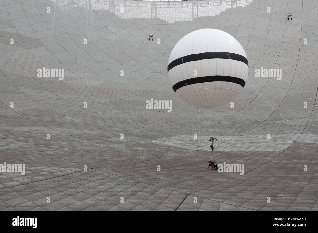 200105 -- BEIJING, Jan. 5, 2020 -- A staff member conducts maintenance of the reflector panels on the Five-hundred-meter Aperture Spherical Radio Telescope FAST with the help of a microgravity mechanism in Pingtang County, southwest China s Guizhou Province, Aug. 30, 2019. Researchers with the China-based FAST, the world s largest single-dish radio telescope, tested a microgravity mechanism in the maintenance of the telescope s 4,450-panel reflector on Aug. 30, 2019. The micro-G mechanism aims to help reduce the maintenance staff s body weight to a value within the reflector panels range of du Stock Photo