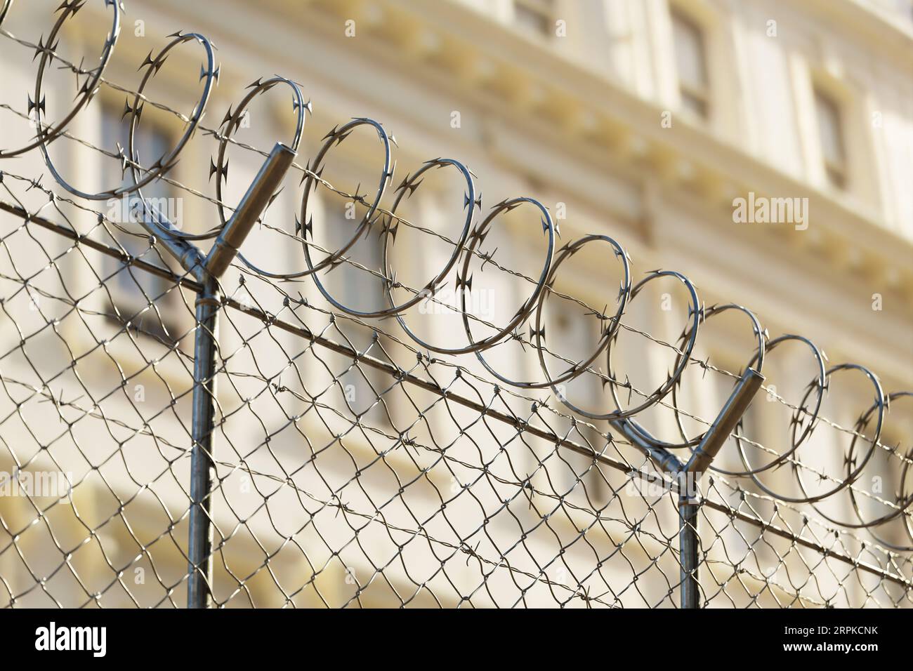 A jail or embassy building surrounded by a tall metal fence with barbed wire Stock Photo Alamy