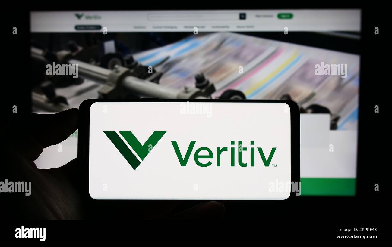 Person holding cellphone with logo of US packaging company Veritiv Corporation on screen in front of business webpage. Focus on phone display. Stock Photo