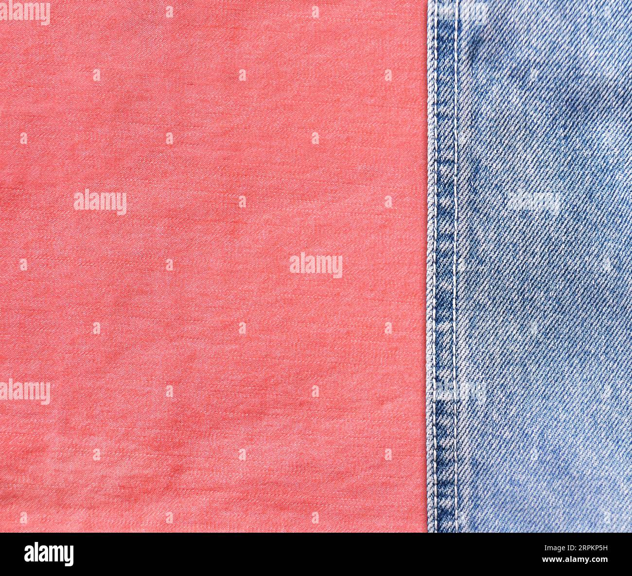 Blue denim borders with a seam and coral cotton texture. Light blue and pink color denim jeans fabric. Copy space for text Stock Photo