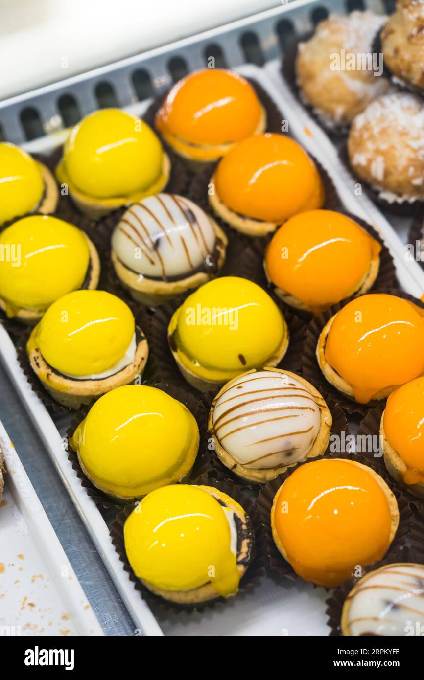 Delicious cakes covered with bright orange and yellow mirror glaze.  Stock Photo