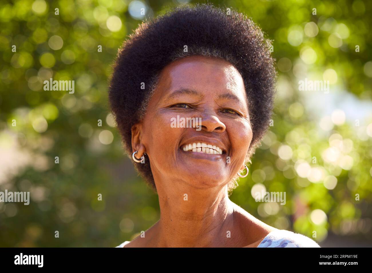 Portrait Of Smiling Senior Woman Standing Outdoors In Garden Park Or Countryside Stock Photo
