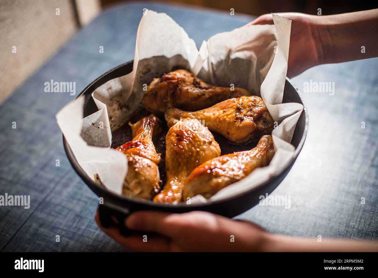 child holds chicken quarter leg in frying pan. Dishes cooked at home. Chicken cooked according