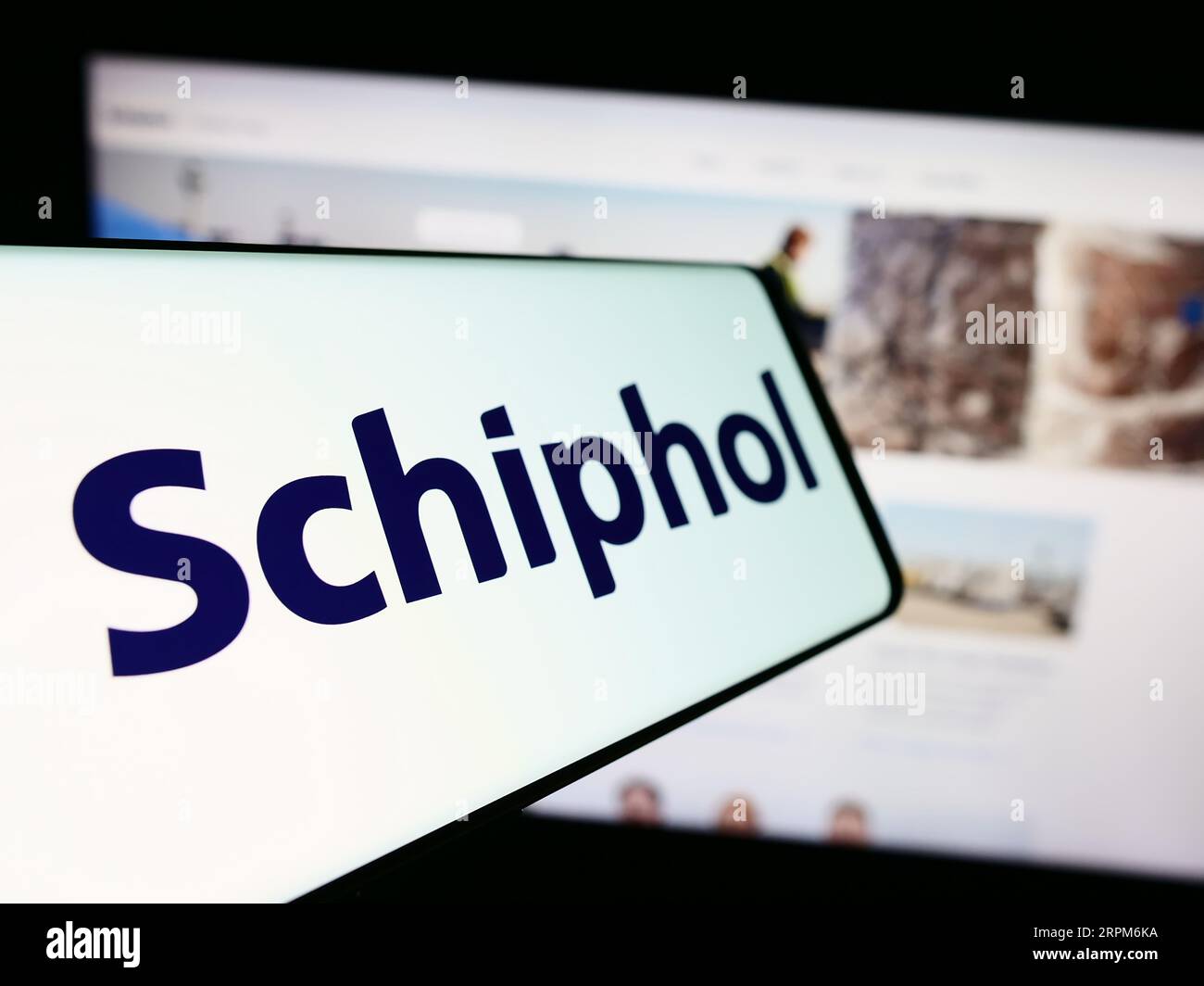 Mobile phone with logo of Dutch airport company Royal Schiphol Group N.V. on screen in front of website. Focus on center-left of phone display. Stock Photo