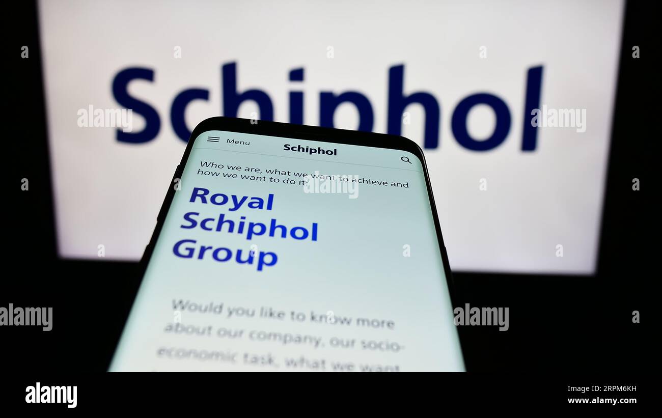 Smartphone with website of Dutch airport company Royal Schiphol Group N.V. on screen in front of logo. Focus on top-left of phone display. Stock Photo