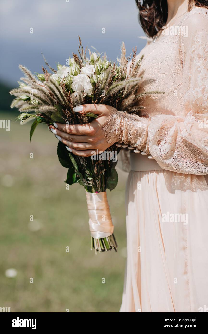 A vertical closeup shot of a bridesmaid in a pink dress holding a bouquet Stock Photo