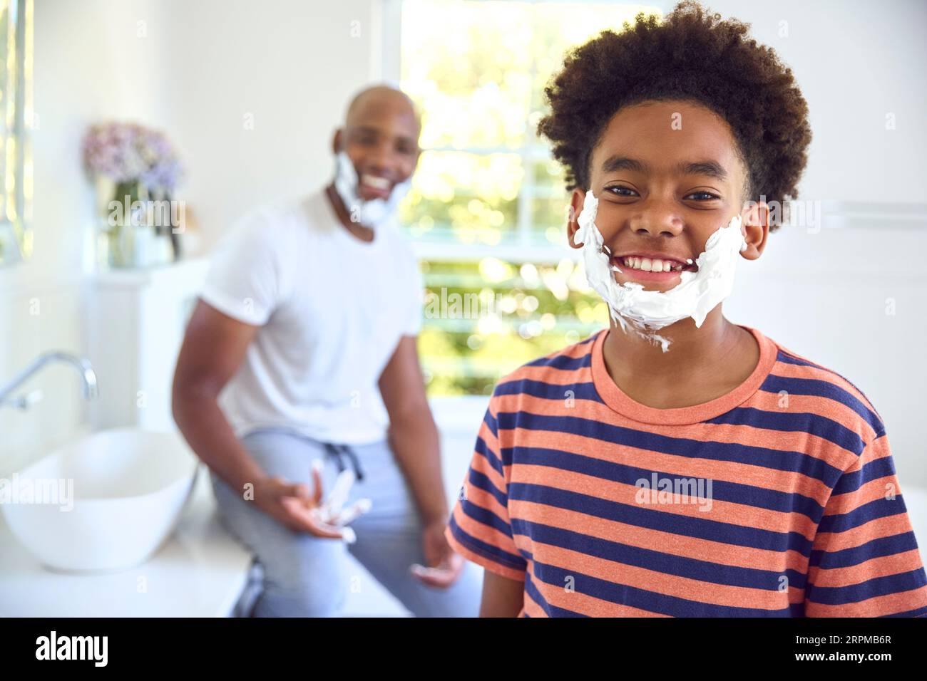 Father And Son At Home Having Fun Playing With Shaving Foam In Bathroom Making A Mess Together Stock Photo