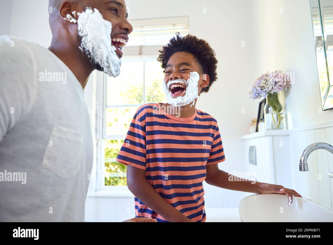 Father And Son At Home Having Fun Playing With Shaving Foam In Bathroom Making A Mess Together Stock Photo