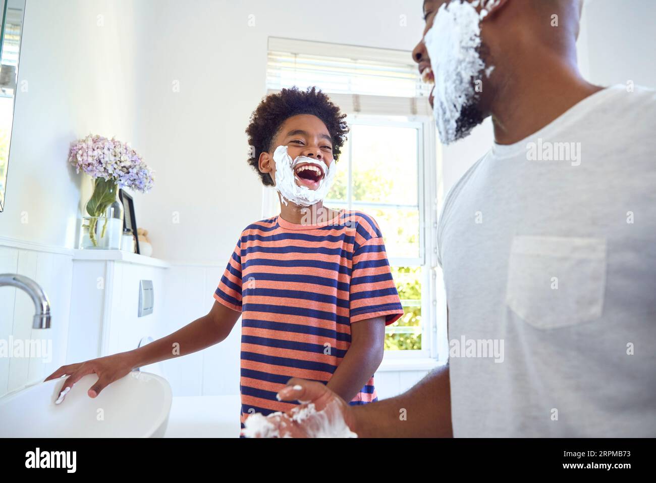 Father And Son At Home Having Fun Playing With Shaving Foam In Bathroom Making A Mess Together Stock Photo