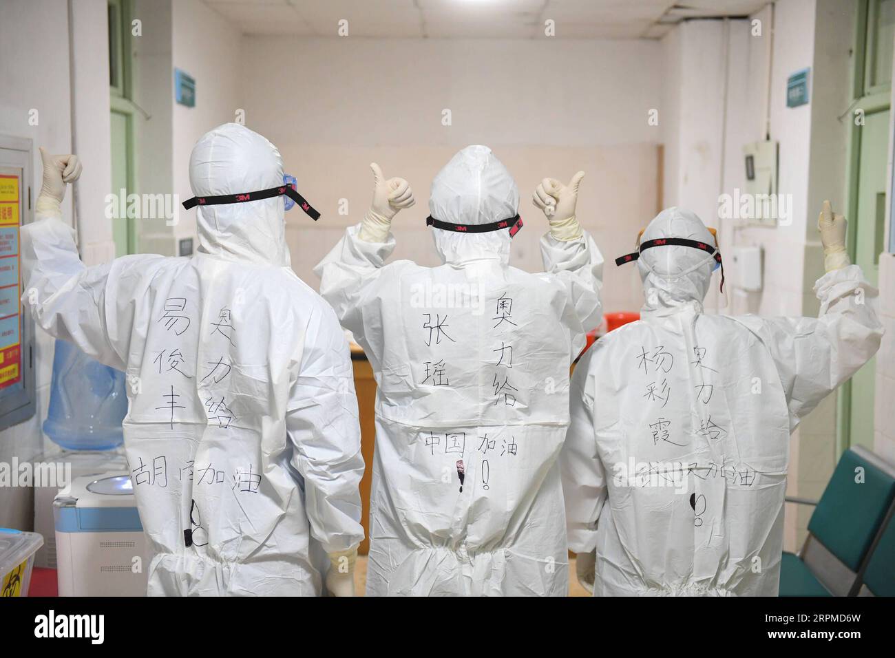 200209 -- CHANGSHA, Feb. 9, 2020 -- Yi Junfeng L, together with his colleagues Zhang Yao C and Yang Caixia, display handwritings on their protective suits in support of the battle against the novel coronavirus outbreak, at Hunan People s Hospital in Changsha, central China s Hunan Province, Feb. 7, 2020. Amid the current novel coronavirus outbreak, 22-year-old male nurse Yi Junfeng has volunteered to join the battle against the epidemic. After a series of professional trainings, he now works as a front-line fever clinic nurse at Hunan People s Hospital in Changsha. Yi believes that a male nurs Stock Photo