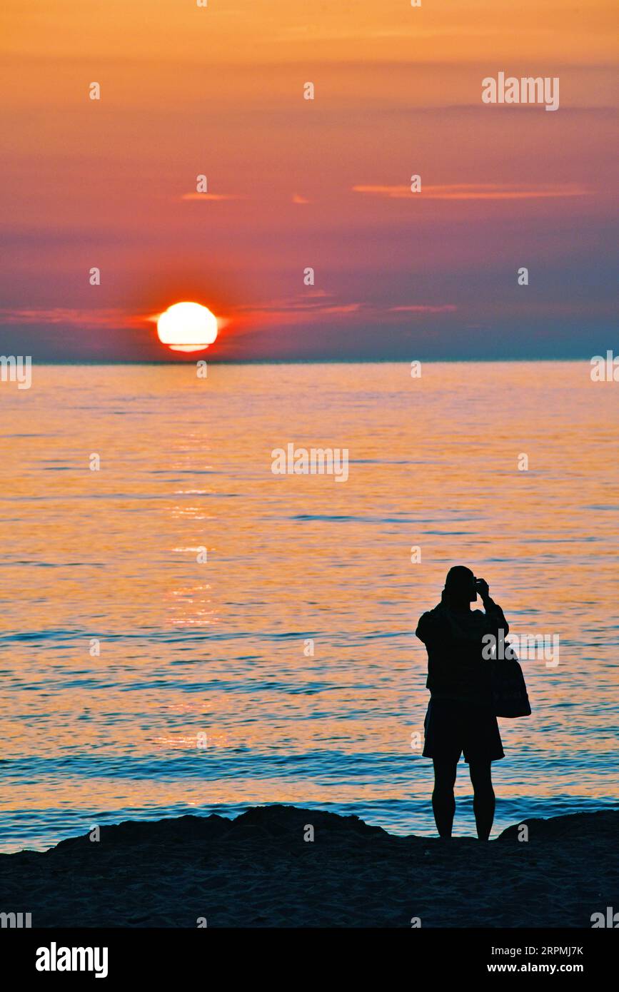 tourist taking photo of sunrise over Mediterranean Sea, France, Corsica, Bastia Stock Photo