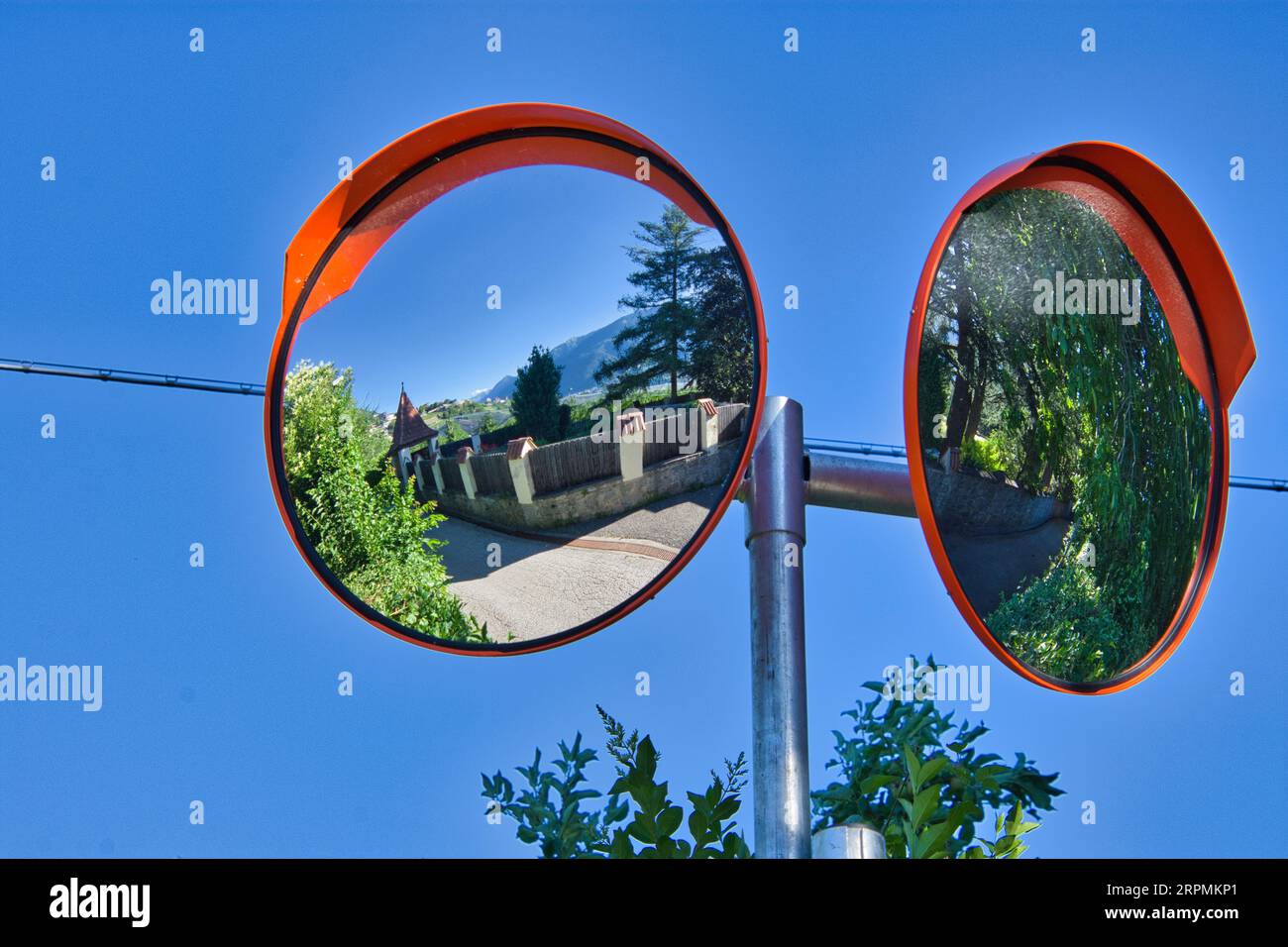 A closeup of a twoway street mirror, reflecting a building and its