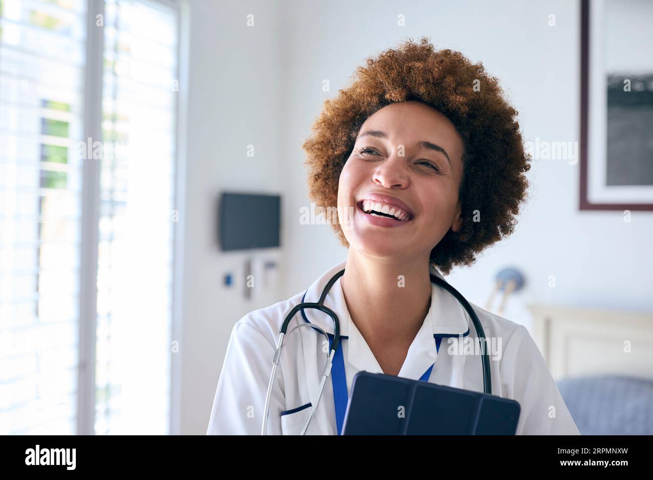 Portrait Of Smiling Female Nurse Wearing Uniform With Digital Tablet In Private Hospital Room Stock Photo