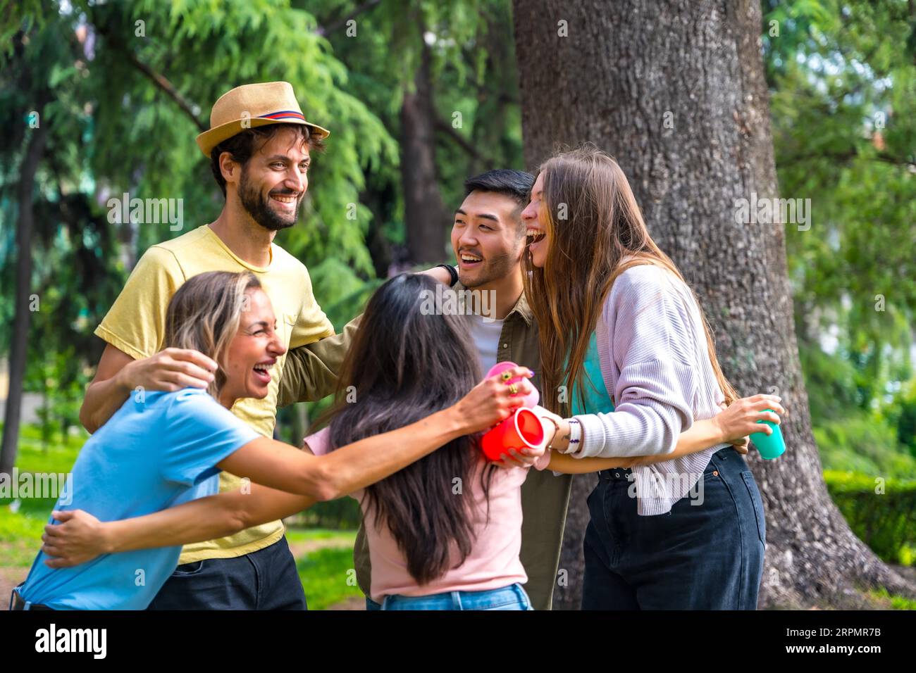 Hugging A Lod Multiethnic group of birthday party in the city park hugging in a ...