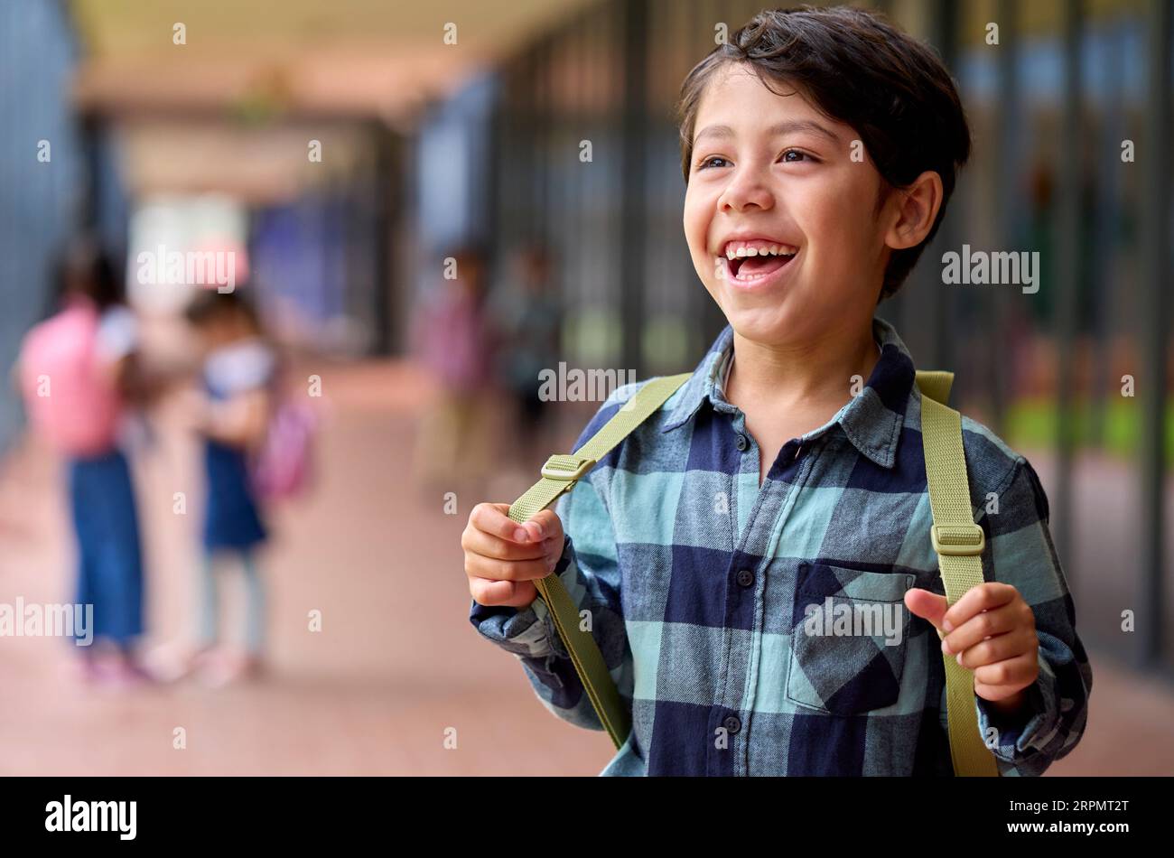 Portrait Of Smiling Male Elementary School Pupil Outdoors With Backpack At School Stock Photo