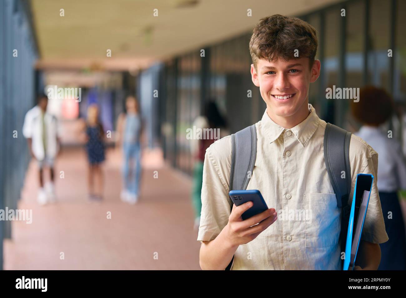 Portrait Of Male Secondary Or High School Student Outdoors At School With Mobile Phone Stock Photo