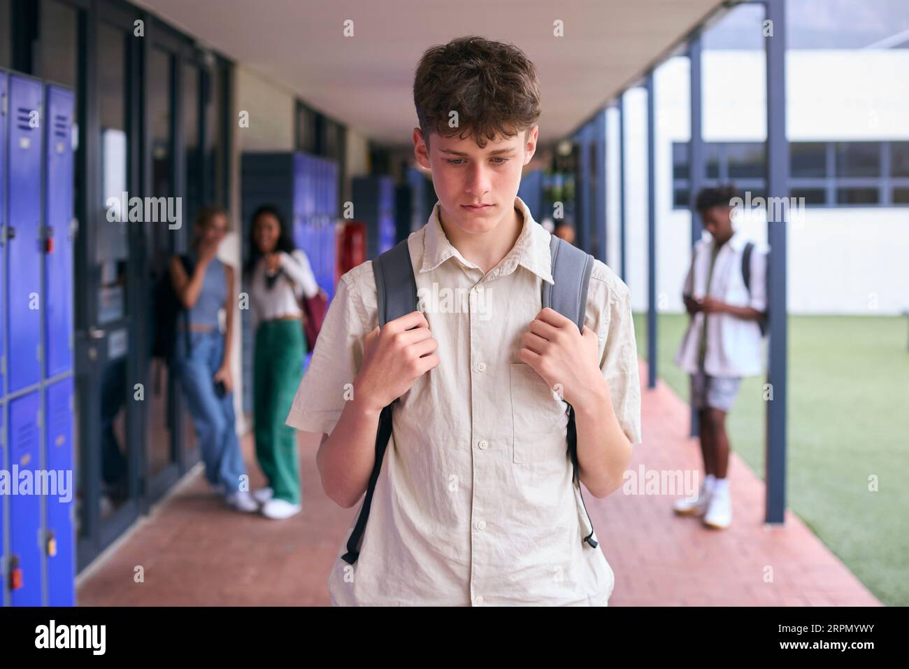 Unhappy Teenage Boy Outdoors At High School Being Teased Or Bullied Stock Photo