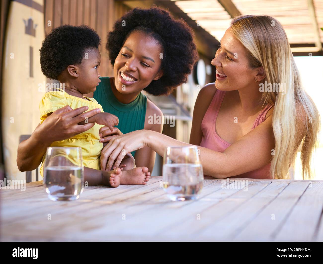 Same Sex Family With Two Mums Playing With Young Daughter Outdoors At Home Stock Photo
