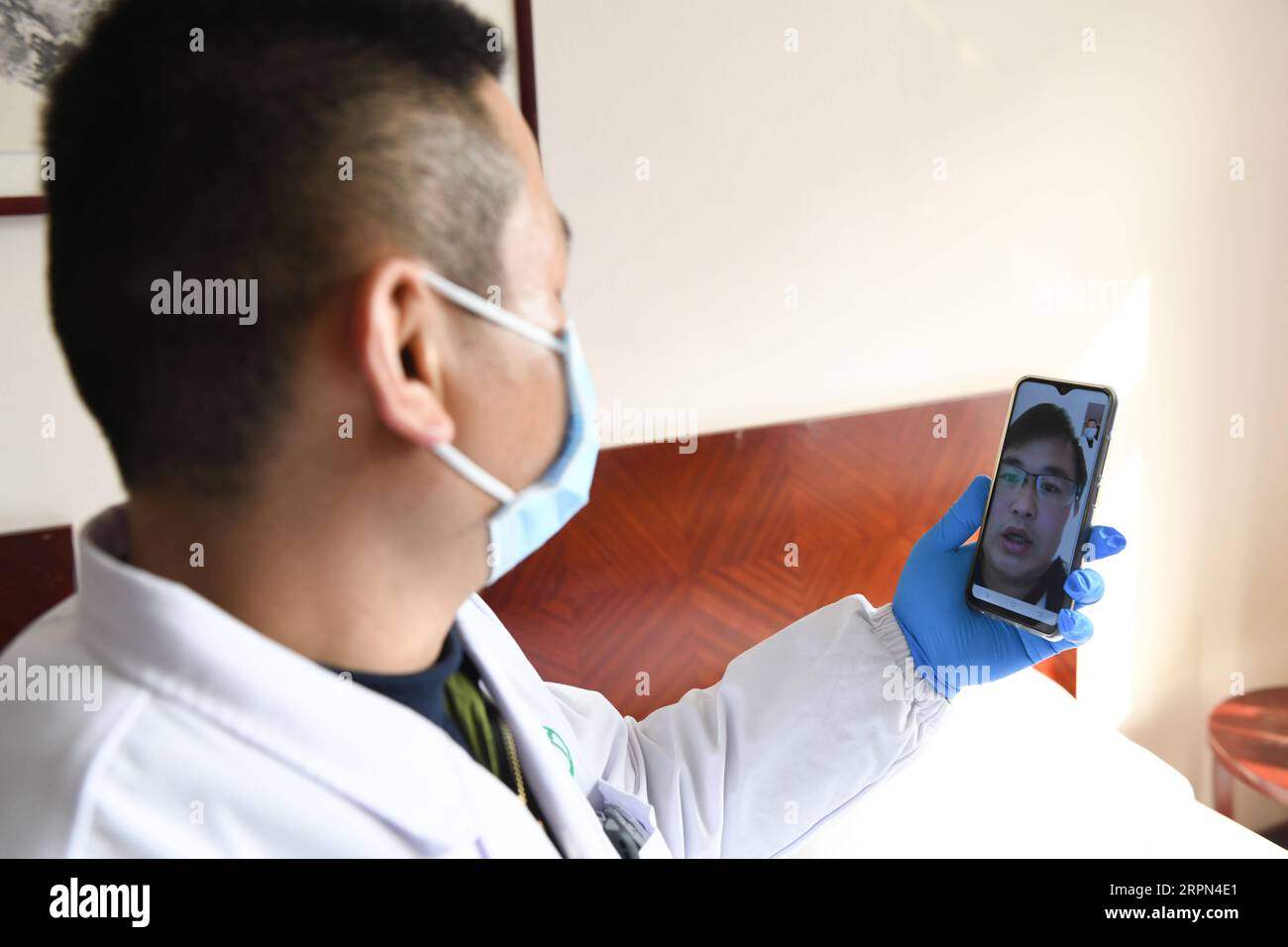 200222 -- HEFEI, Feb. 22, 2020 -- Health worker Li Hao of Yonghe health station in Changning Community has a video chat with a staff member in quarantine who didn t feel well a couple of days ago in Hefei, east China s Anhui Province, Feb. 21, 2020. Thirty five staff members of the Anhui Branch of China Construction Eighth Engineering Division Corp. Ltd., who attended the construction of the makeshift Leishenshan hospital for novel coronavirus pneumonia patients in Wuhan, have recently come back to Hefei. They are now in quarantine for medical observation in a hotel in Hefei. Each of them has Stock Photo