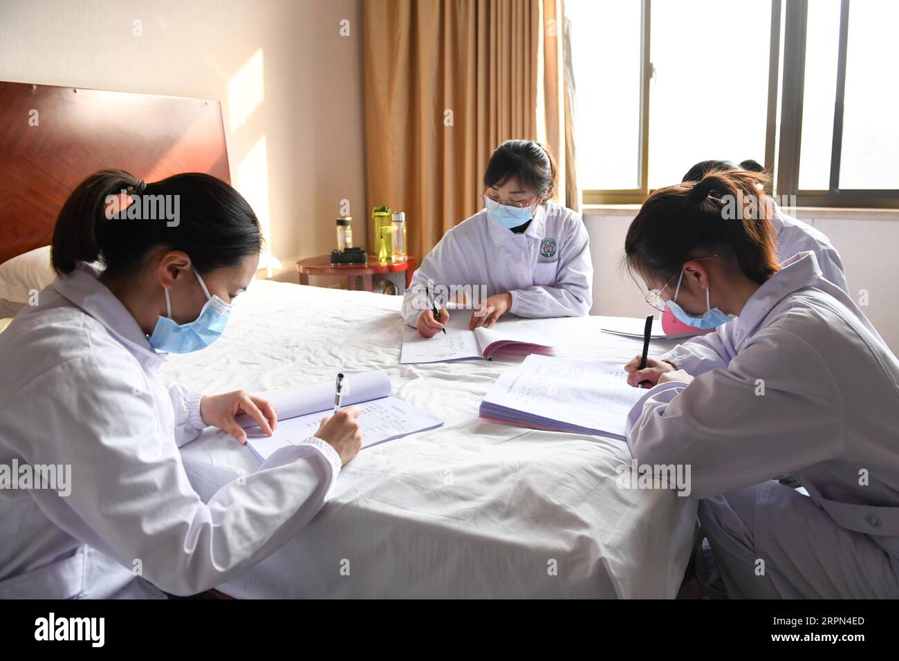 200222 -- HEFEI, Feb. 22, 2020 -- Health workers of Yonghe health station in Changning Community register body temperature of staff members in quarantine in Hefei, east China s Anhui Province,Feb. 21, 2020. Thirty five staff members of the Anhui Branch of China Construction Eighth Engineering Division Corp. Ltd., who attended the construction of the makeshift Leishenshan hospital for novel coronavirus pneumonia patients in Wuhan, have recently come back to Hefei. They are now in quarantine for medical observation in a hotel in Hefei. Each of them has a separate room which is disinfected every Stock Photo
