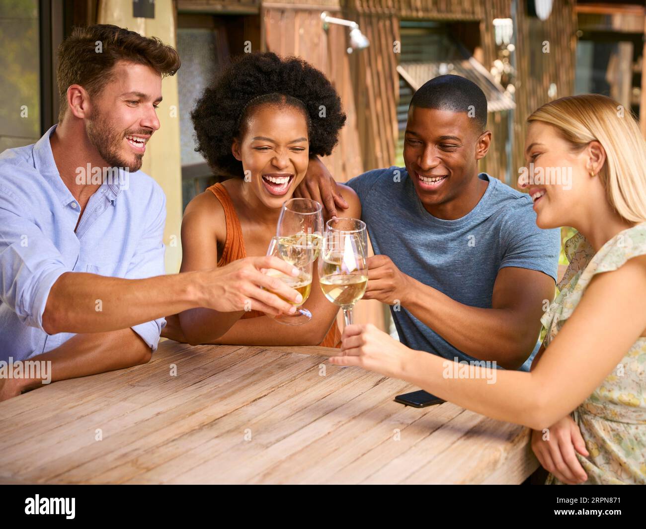 Group Of Smiling Multi-Cultural Friends Outdoors At Home Drinking Wine Together Stock Photo
