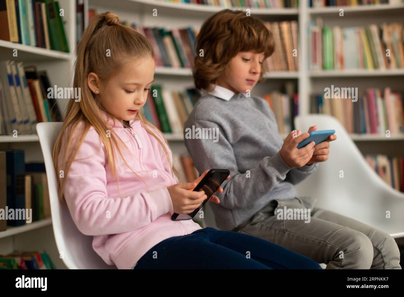 School kids using smartphones during break after classes, playing games or watching videos online on mobile phones Stock Photo