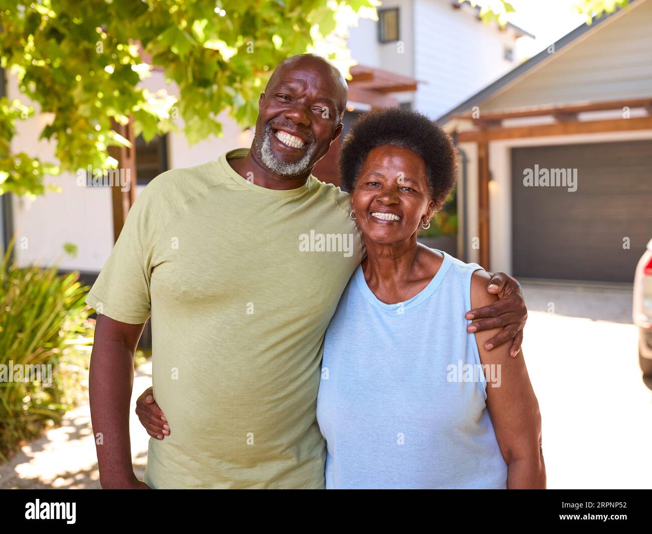 Portrait Of Loving Senior Couple Outdoors Hugging In Front Of Home Stock Photo