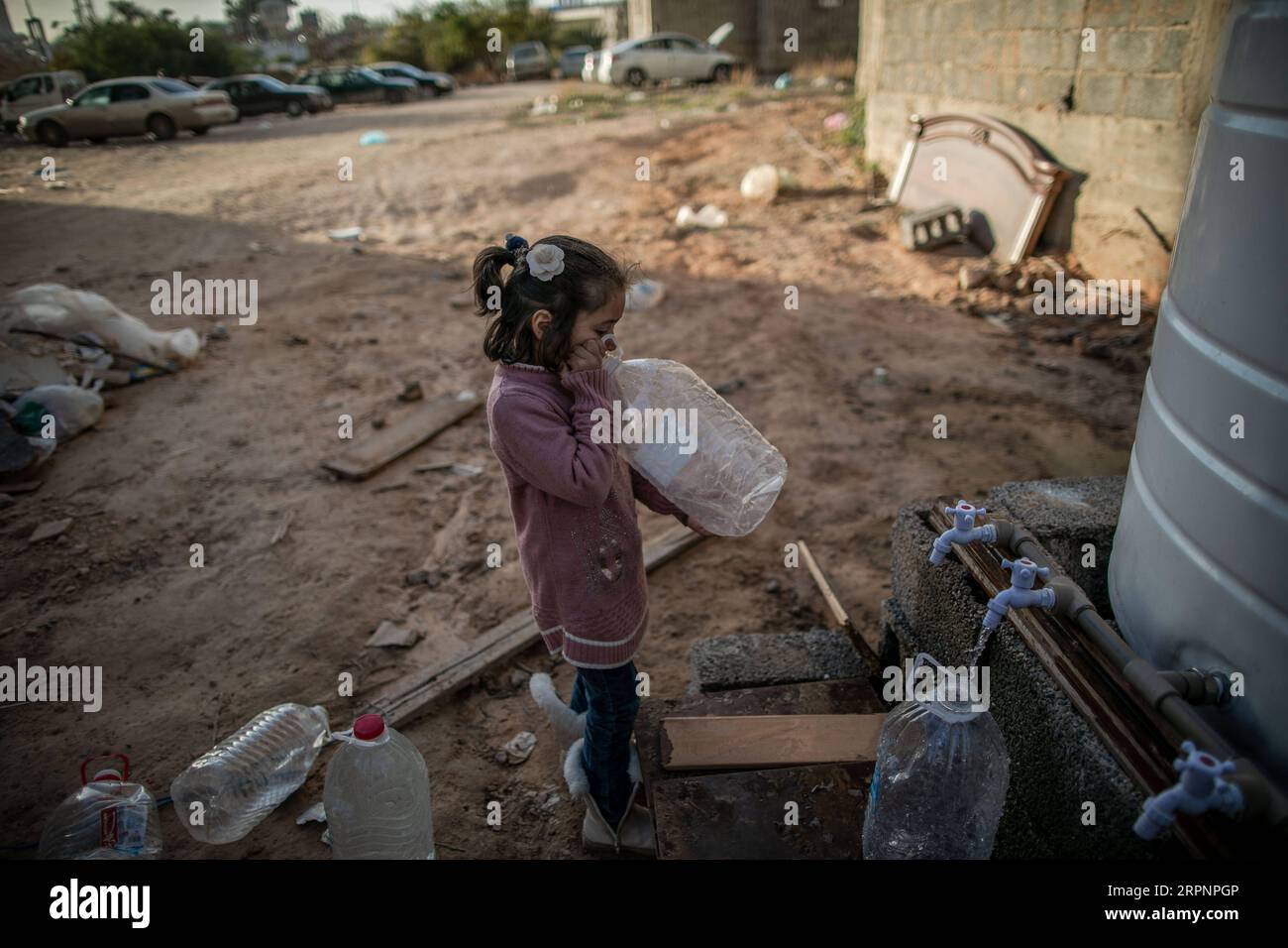 200303 -- TRIPOLI, March 3, 2020 -- A displaced girl drinks water from a well in a building complex under construction, where hundreds of displaced families live, in Tripoli, Libya, March 2, 2020. According to the data of UN High Commissioner for refugees UNHCR, more than 350,000 Libyans are currently internally displaced. Photo by Amru Salahuddien/Xinhua LIBYA-TRIPOLI-DISPLACED CHILDREN PanxXiaojing PUBLICATIONxNOTxINxCHN Stock Photo