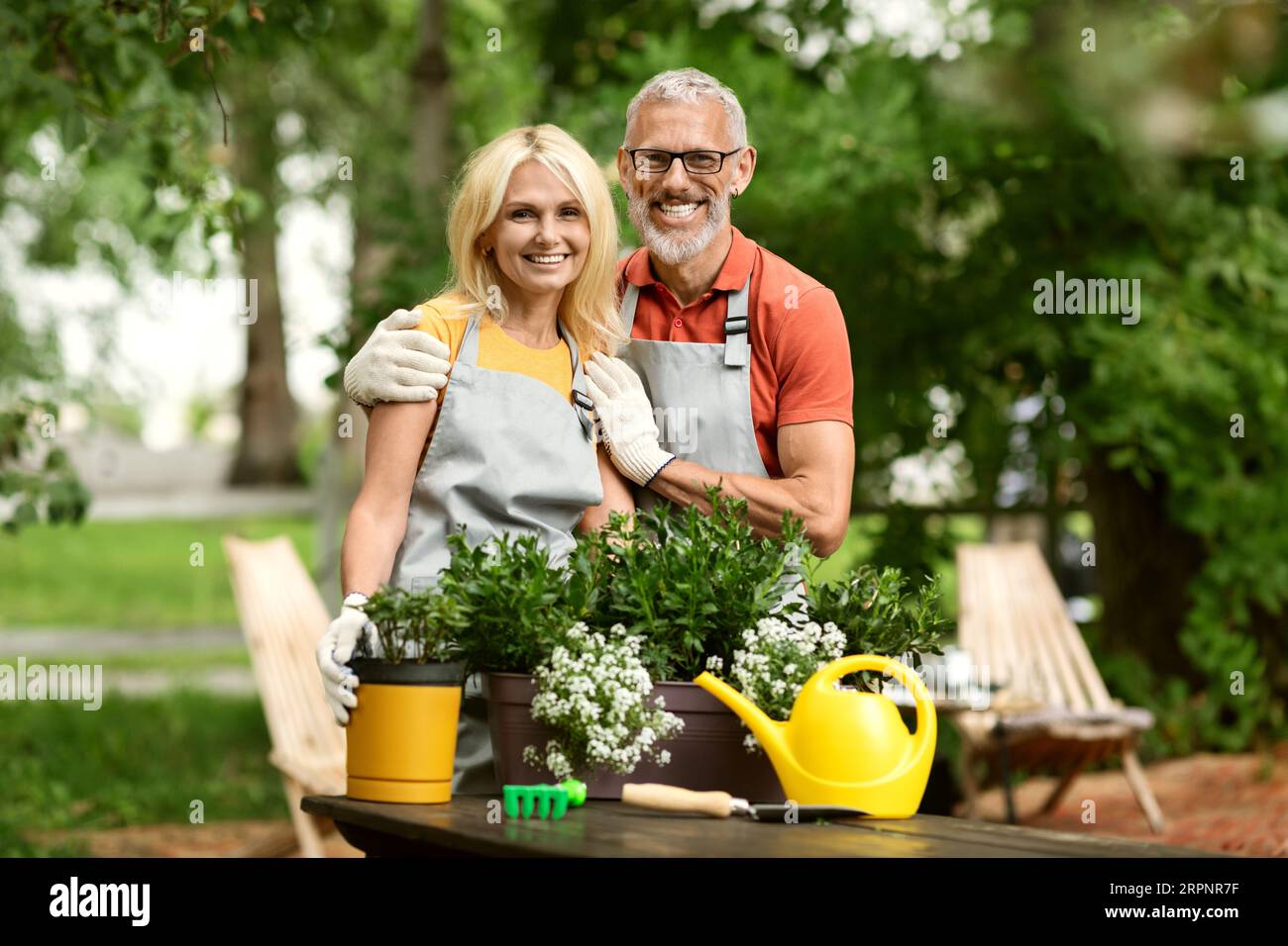 Portrait Of Happy Mature Couple Replanting Potted Flowers In Garden portrait-of-happy-mature-couple-replanting-potted-flowers-in-garden