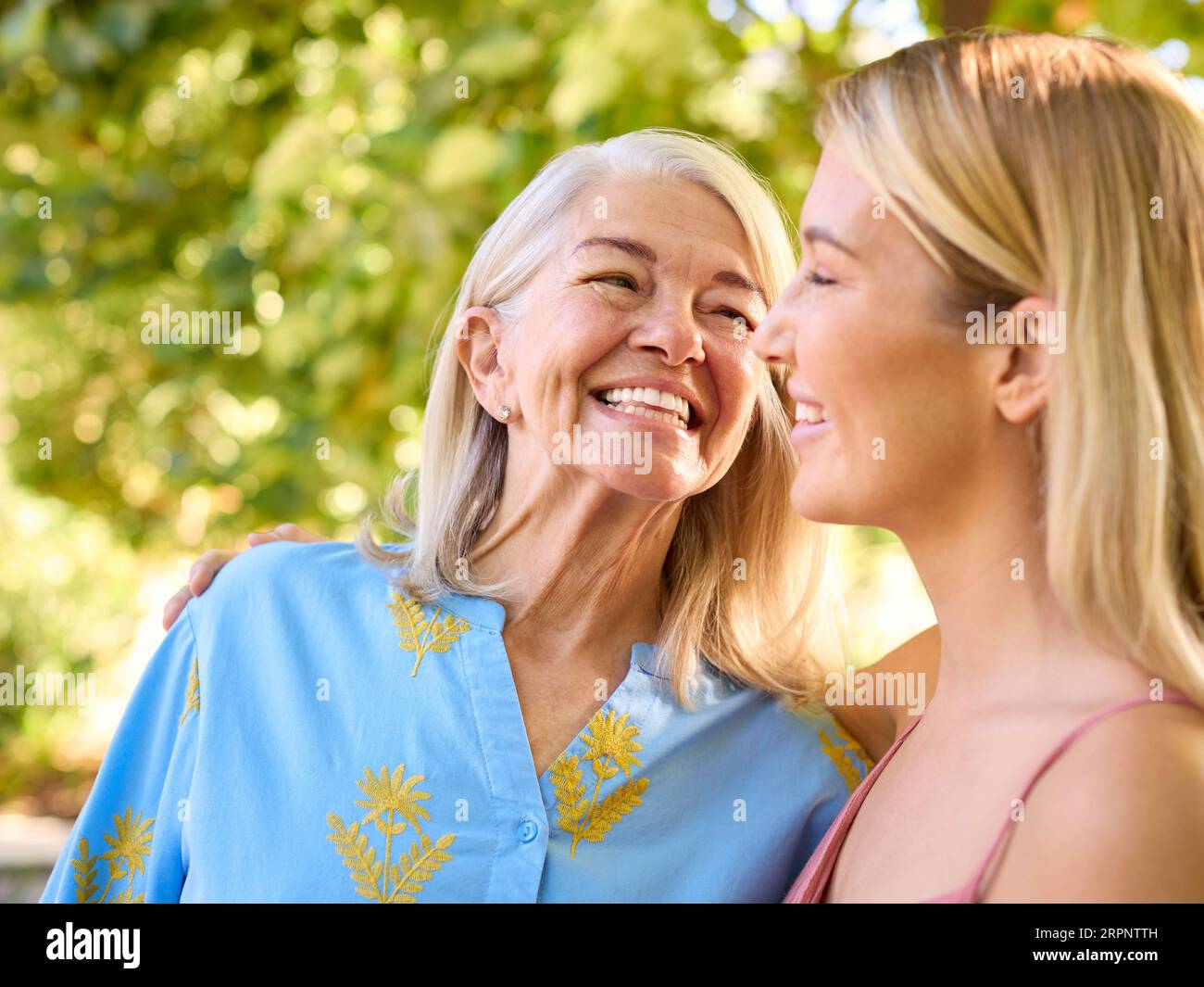 Multi-Generation Family With Senior Mother And Adult Daughter Laughing In Garden Stock Photo