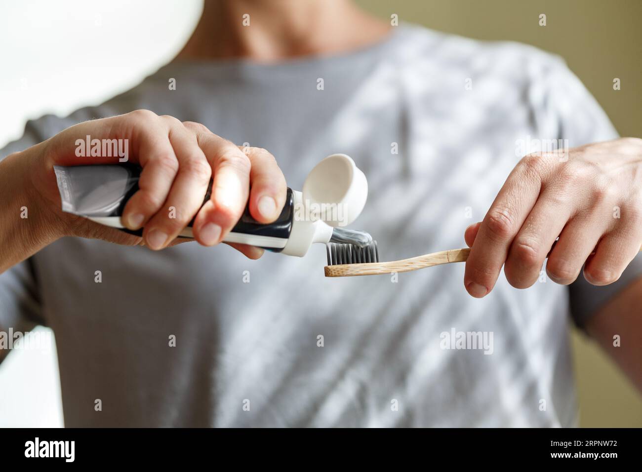 Applying toothpaste on a bamboo tooth brush. Hands squeezing tube with a toothpaste. Dentistry and hygenic concept. Stock Photo