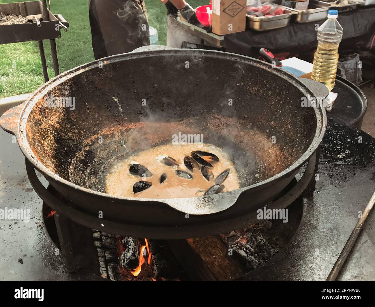 cook prepares mussels seafood in a vat on a fire steaming in oil