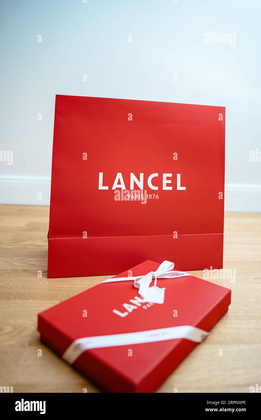 Paris, France - Aug 25, 2023: Front view of Lancel Paris branded red gift box with elegant logotype and silk ribbon on he wooden floor. A symbol of luxury and sophistication. Perfect for presentations and events. Stock Photo