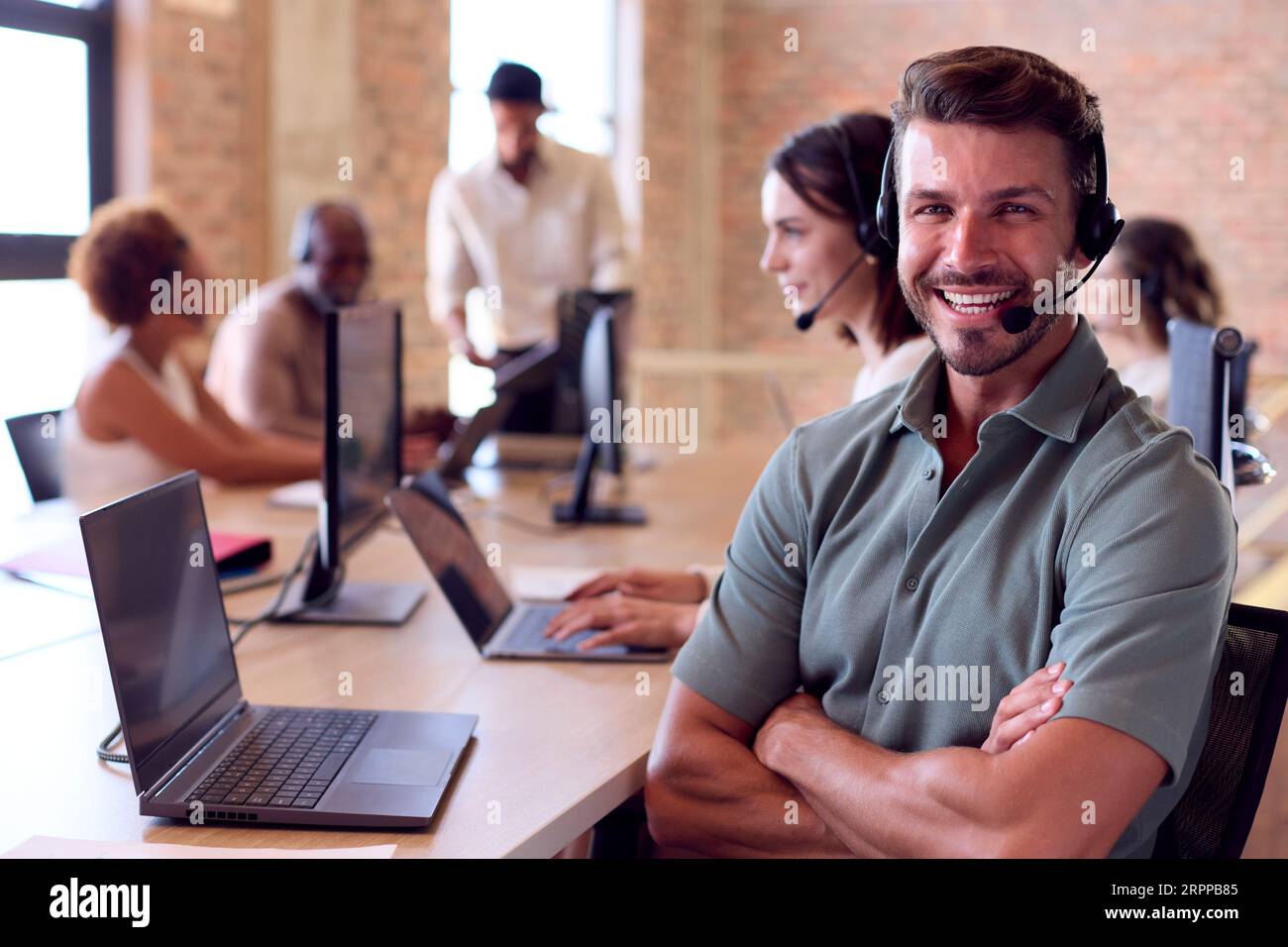Businessman In Multi-Cultural Business Team Wearing Headsets In Customer Support Centre Stock Photo