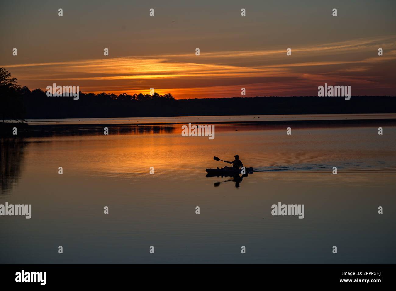 Man paddling his kayak at sunset on the lake at Little Black Creek ...