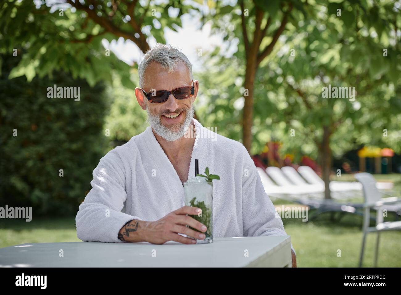 wellness retreat concept, happy middle aged man in sunglasses and robe ...