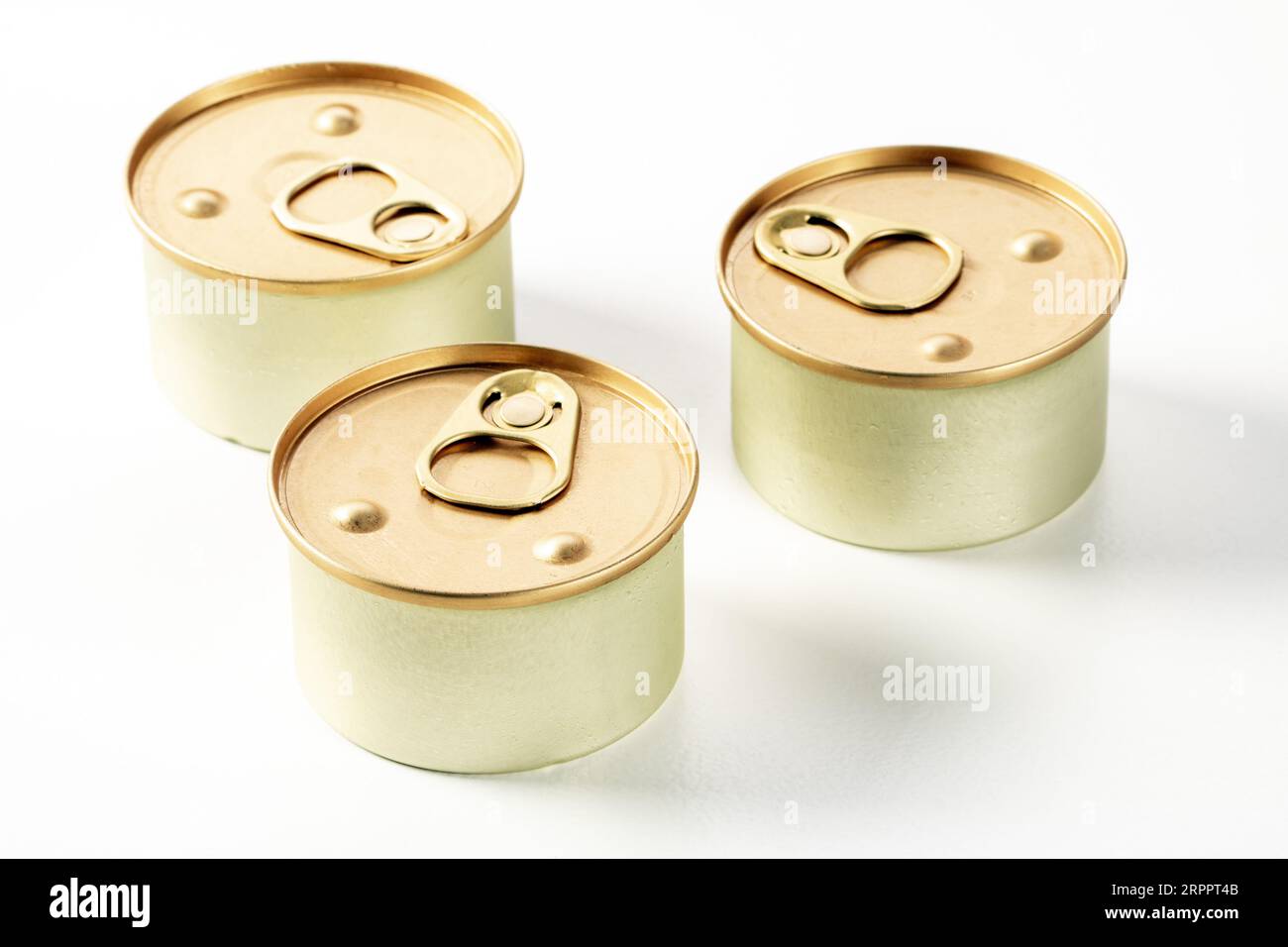 Three metal cans of cat food on a white background. Drops of condensate are visible on the cans, they have just been taken out of the refrigerator Stock Photo