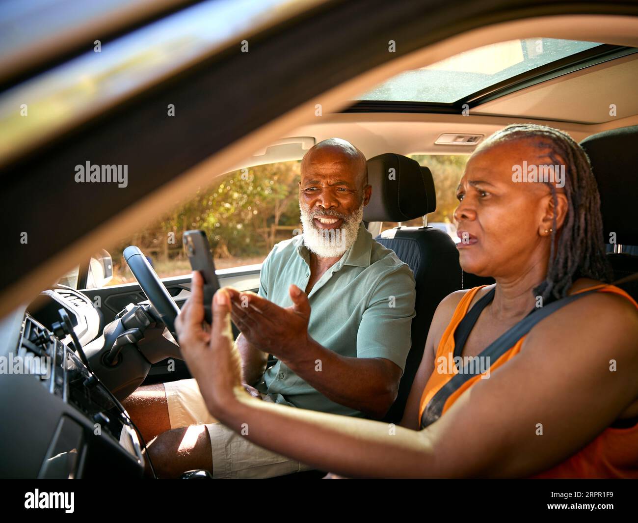Senior Couple In Car Arguing About Directions On GPS Sat Nav On Mobile Phone On Day Trip Out Stock Photo