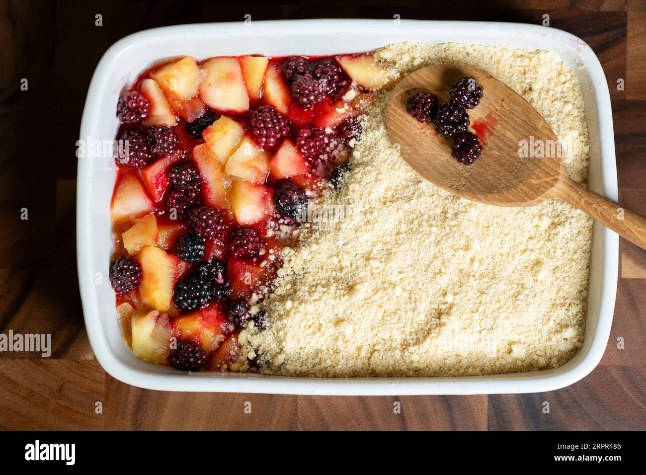 A homemade traditional english apple and blackberry crumble. The pie made with locally foraged wild fruit and is in a large ceramic baking dish Stock Photo